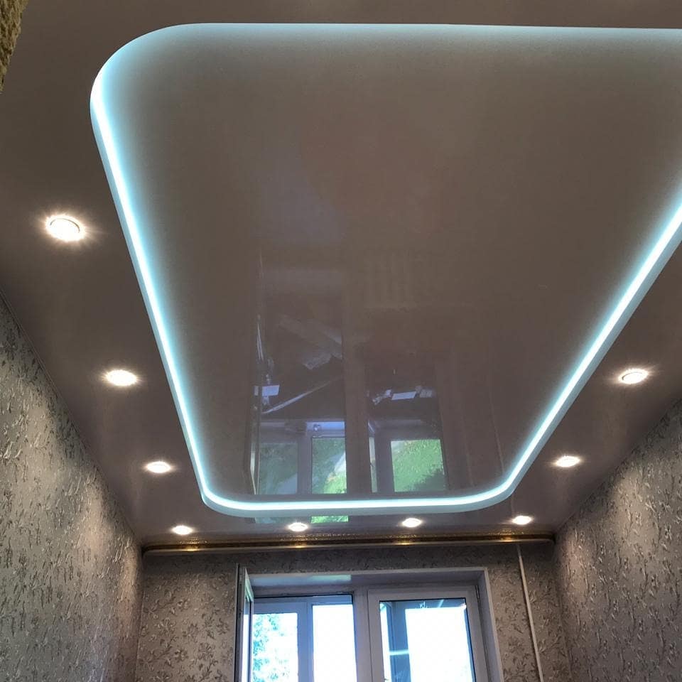 Двухуровневый глянцевый натяжной потолок с подсветкой и точечными светильниками.