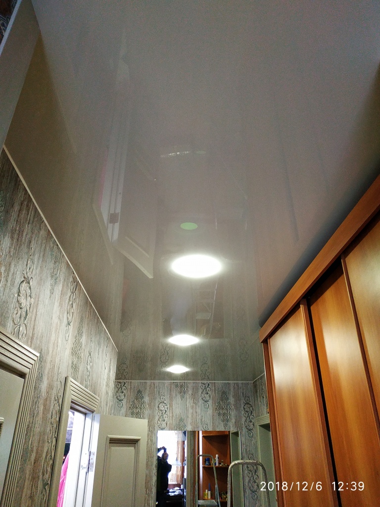 глянцевый натяжной потолок в коридоре с точечными светильниками, вид на фоне мебели